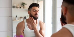 Hombre atractivo cuida su barba en el baño y disfruta con ello